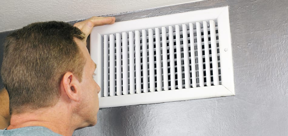 A man is inspecting the air ducts before determining if they need cleaning. 